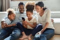 Loving young biracial family with kids using smartphone at home Royalty Free Stock Photo