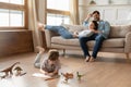 Parents relaxing on sofa, watching little kid son drawing pictures.