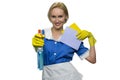 Smiling maid holding rag and pointing spray gun at camera on white background.