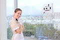 A smiling maid remotely controls a robot window cleaner. Room service. Cleaning in the hotel or in the house. Copy of the space