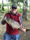 Smiling male angler showing his wife and children fish which he catched yesterday in morning on lake, having happy expression Royalty Free Stock Photo