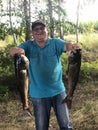 Smiling male angler showing his wife and children two fish which he catched yesterday in morning on lake, having happy expression Royalty Free Stock Photo