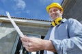 smiling male architect holding plans outside property Royalty Free Stock Photo