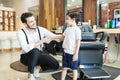 Smiling Male Barber Greeting Little Customer In Salon