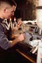 Smiling male barista using professional coffee machine enjoying job in cafe improving skills of making cappuccino Royalty Free Stock Photo