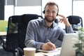 Smiling male call-center operator with headphones sitting at modern office Royalty Free Stock Photo