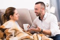 Smiling male is careing for his wife and offering her cup of tea Royalty Free Stock Photo