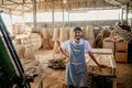 smiling male carpenter standing casually in a woodcraft warehouse