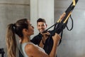 Smiling male Coach helps woman with suspension strap workout at gym hiit class. Royalty Free Stock Photo