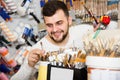 smiling male customer examining various types of brushes in paint store Royalty Free Stock Photo