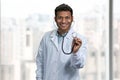 Smiling male doctor looking at camera and showing stethoscope.