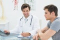 Smiling male doctor writing reports besides patient Royalty Free Stock Photo