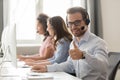 Smiling male employee in headset show thumb up Royalty Free Stock Photo