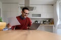 Smiling male financial adviser holding reports and working over laptop at desk in home office Royalty Free Stock Photo