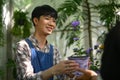 Smiling male florist giving plant in a pot to female customer at his floral shop. Floristry and small business concept. Royalty Free Stock Photo