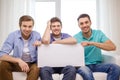 Smiling male friends holding white blank board Royalty Free Stock Photo