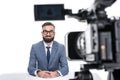 smiling male newscaster in suit sitting in front of camera,