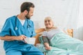 smiling male nurse with stethoscope holding blood pressure monitor while measuring blood pressure to senior woman Royalty Free Stock Photo