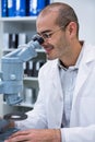 Smiling male optometrist looking through microscope