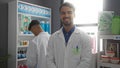 Smiling male pharmacists working together in a well-organized pharmacy store interior