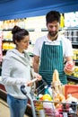 Smiling male staff assisting a woman with grocery shopping Royalty Free Stock Photo