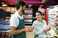 Smiling male staff assisting a woman with grocery shopping