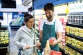 Smiling male staff assisting a woman with grocery shopping Royalty Free Stock Photo