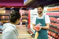 Smiling male staff assisting a woman with grocery shopping Royalty Free Stock Photo