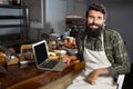 Smiling male staff using laptop at counter in bakery shop