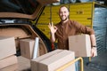 Happy young man holding a box and showing ok Royalty Free Stock Photo