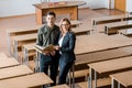 Smiling male student and female teacher holding university books and looking at camera Royalty Free Stock Photo