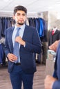 Smiling male is trying on tie in front of the mirror