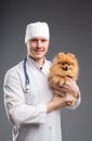 Smiling male vet with phonendoscope holding cute pomeranian dog Royalty Free Stock Photo