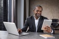 Smiling male in white shirt and black jacket using two electronic gadgets for optimisation of working process Royalty Free Stock Photo