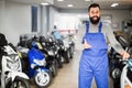 Smiling male worker demonstrating motorcycles Royalty Free Stock Photo