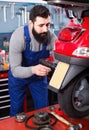 Smiling male worker fixing failed motorcycle Royalty Free Stock Photo