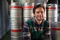 Smiling male worker sitting by kegs at warehouse Royalty Free Stock Photo