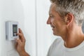 Smiling Man Adjusting Thermostat On Home Heating System Royalty Free Stock Photo