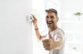 Smiling Man Adjusting Thermostat On Home Heating System Royalty Free Stock Photo