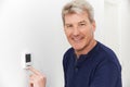Smiling Man Adjusting Thermostat On Home Heating System Royalty Free Stock Photo