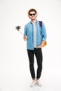 Smiling man with backpack and mobile phone on selfie stick Royalty Free Stock Photo