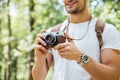 Smiling man with backpack taking photos using vintage camera outdoors Royalty Free Stock Photo