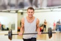 Smiling man with barbell in gym