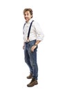 A smiling man with a beard in a white shirt and jeans stands holding his hands in his pockets. Full height. Isolated on a white Royalty Free Stock Photo