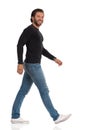 Smiling Man In Black Jersey, Jeans And Sneakers Is Walking And Looking At Camera. Side View Royalty Free Stock Photo
