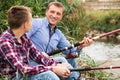 Smiling man and boy fishing together on river Royalty Free Stock Photo