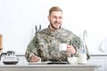 Smiling man in camouflage uniform writing in notebook and Royalty Free Stock Photo