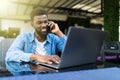 Smiling man in a conversation over phone outdoor cafe. Happy african guy talking on mobile phone and looking away. Smiling student Royalty Free Stock Photo