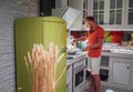 Smiling man cooking morning breakfast on the cozy home kitchen with a bright green fridge. He frying something delicious in the Royalty Free Stock Photo