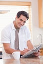 Smiling man doing crossword puzzle in the kitchen Royalty Free Stock Photo